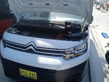 Furgón blanco recibiendo pase de corriente en la calle