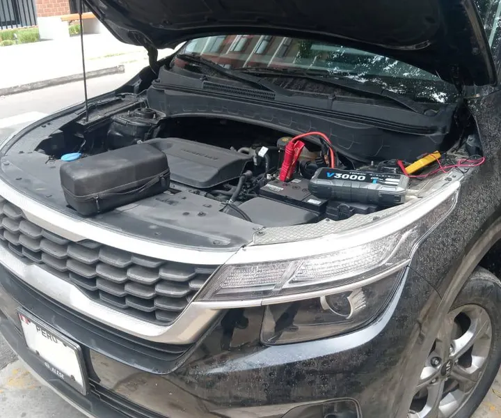 Arrancador conectado a la batería de una camioneta con el capó abierto