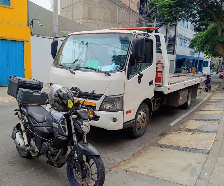Moto con baúl de herramientas estacionada junto a un camión durante una asistencia